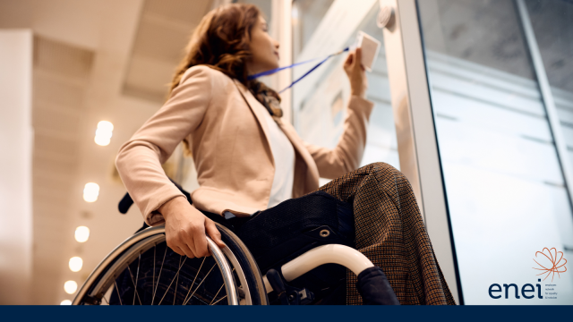 Image shows a female in a wheelchair wearing business clothing holding a lanyard up to a door sensor.